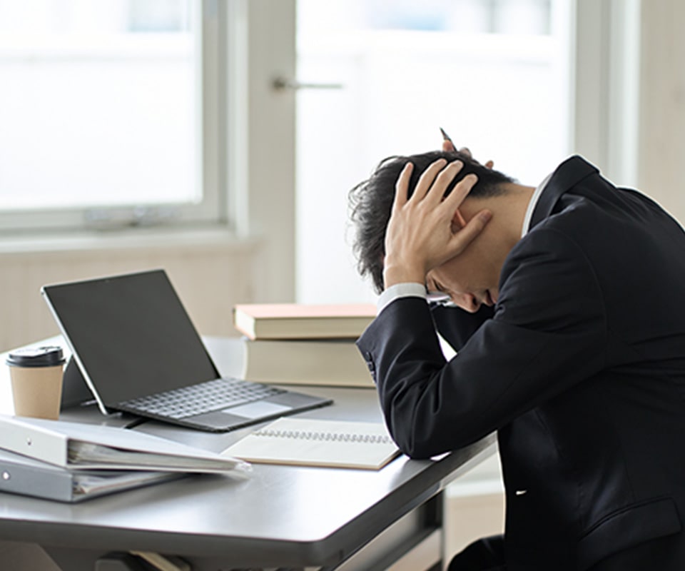 デスクで頭を抱える男性
